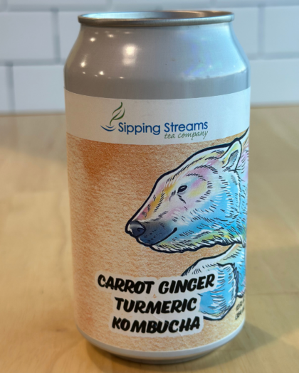 A 12 oz can of Sipping Streams Tea Company's Carrot Ginger Turmeric Kombucha, decorated with a polar bear illustration and earthy orange tones. This probiotic-rich kombucha blends carrot, ginger, and turmeric for a naturally fermented, immune-supporting drink with a refreshing taste.