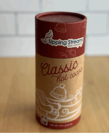 A sleek 8 oz canister of Classic Hot Chocolate mix from Sipping Streams Tea Company, featuring elegant packaging and filled with a rich cocoa blend made from high-quality, natural ingredients.