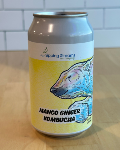 A 12 oz can of Sipping Streams Tea Company's Mango Ginger Kombucha, designed with a bright yellow label featuring a polar bear illustration. This probiotic-rich kombucha combines sweet mango and spicy ginger for a tangy, refreshing beverage packed with gut-health benefits.