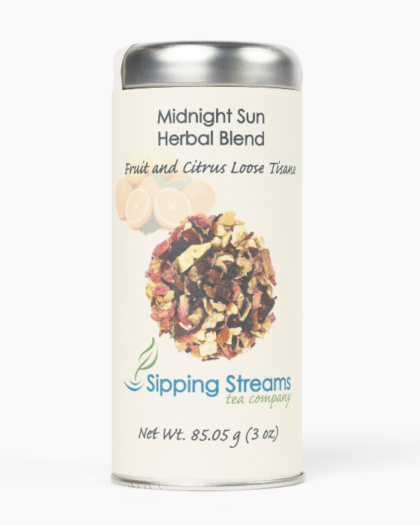 A tall tin of Sipping Streams Tea Company's Midnight Sun Herbal Blend. The label displays dried fruit and citrus ingredients, indicating it is a caffeine-free, fruit and citrus loose tisane. The tin contains 3 oz of loose-leaf tea