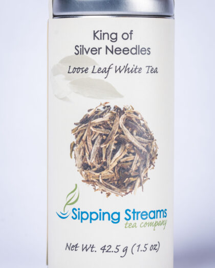 A tall retail tin filled with King of Silver Needles white tea, featuring downy silver buds prized for their smooth, refined flavor.