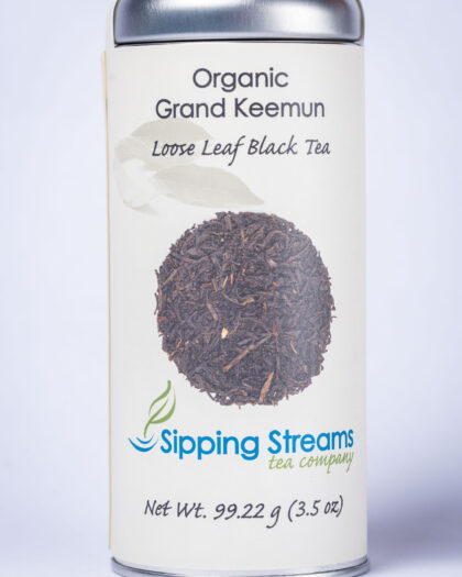 A tall retail tin filled with Organic Grand Keemun black tea, showcasing fine twisted leaves known for their smooth, lightly smoky, and naturally sweet flavor.