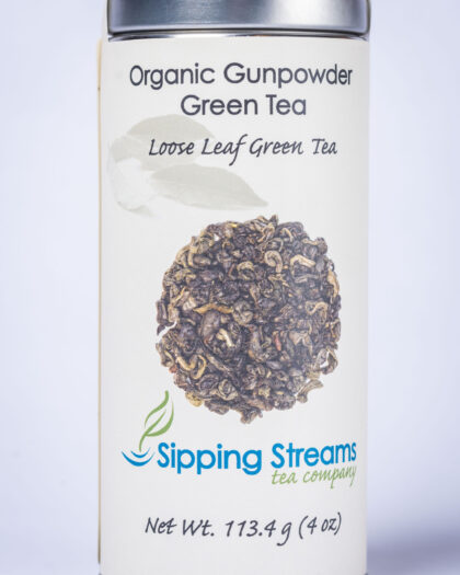 A tall retail tin filled with Organic Gunpowder Green Tea, showcasing tightly rolled green tea pearls that unfurl during steeping for a robust, invigorating cup.
