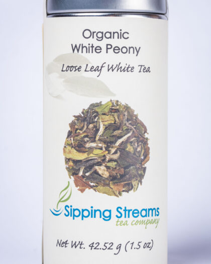 A tall retail tin filled with Organic White Peony white tea, showcasing whole tea leaves and buds known for their soft floral aroma and smooth finish.