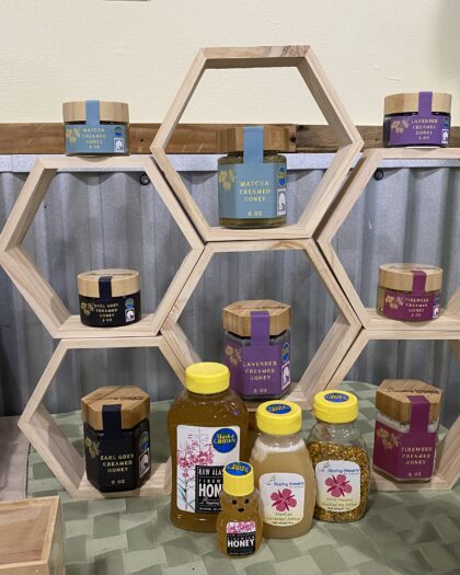 Wooden hexagon honey display rack designed to hold multiple jars of creamed honey for retail countertop merchandising.